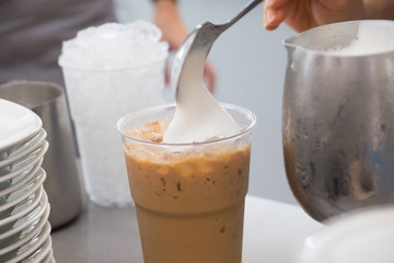 Barista is putting milk foam on coffee.