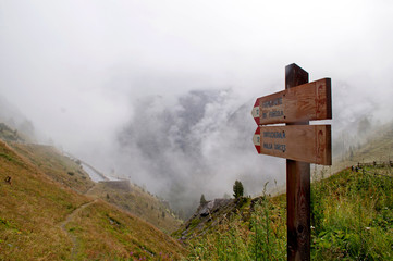 Swiss Alps in the clouds and signs with hiking trails