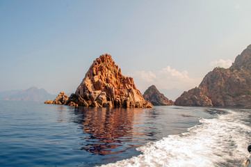 Corsica, France - Sunrise-lit rocks jut out from the sea.
