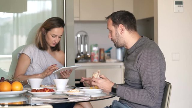 Couple fighting, arguing during meal at home, woman using tablet 

