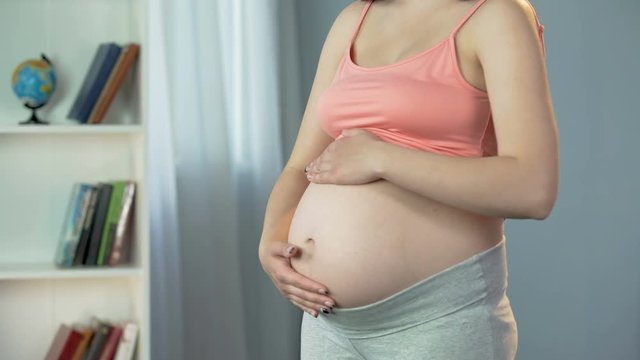 Pregnant woman anticipating birth of baby, touching her belly with tender love