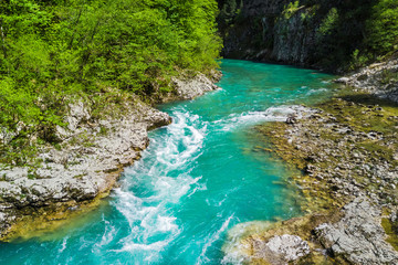 Fototapeta premium Top view of the river in the mountains surrounded by a green forest