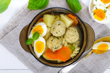 A bowl of soup with chicken meat balls, vegetables, boiled egg and fusilli. Top view.