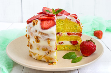 Biscuit cake with fresh strawberries and cream on a white wooden background.