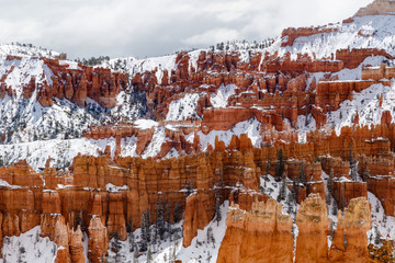 Rugged Landscape of Bryce Canyon National Park, Utah. The rugged, rocky landscape of the valley's opposite wall is seen with giant rock hoodoos, pine trees and a layer of snow.  
