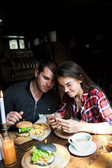 A loving couple sitting in a cafe and looking into the phone
