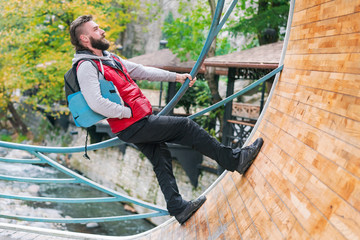 Man in a red vest and backpack going along a round boardwalk track