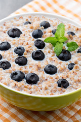 Buckwheat porridge in a bowl with mint leaves and blueberries.