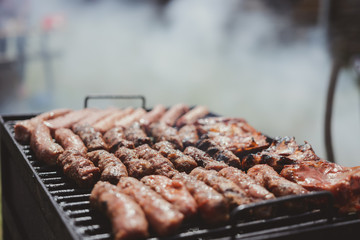 Different type of meats cooked outside, on a hot grill barbecue.