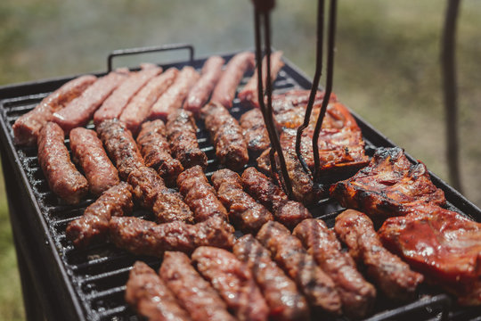 Different type of meats cooked outside, on a hot grill barbecue.