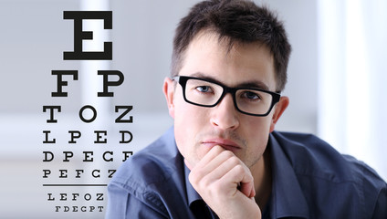 male face with spectacles on eyesight test chart background, eye examination ophthalmology concept