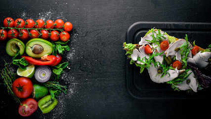 Bruschetta with fresh vegetables and chicken. On Wooden background. Top view. Free space.