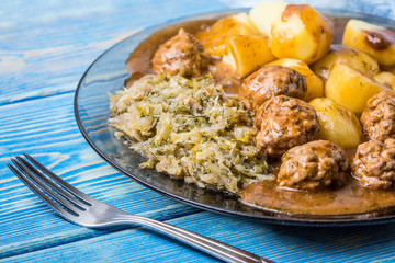 Homemade fried meatballs served with potatoes and cabbage.