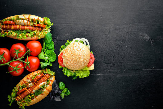 Hot Dog And Hamburger With Cheese, Meat And Greens On Wooden Background. Top View. Free Space.