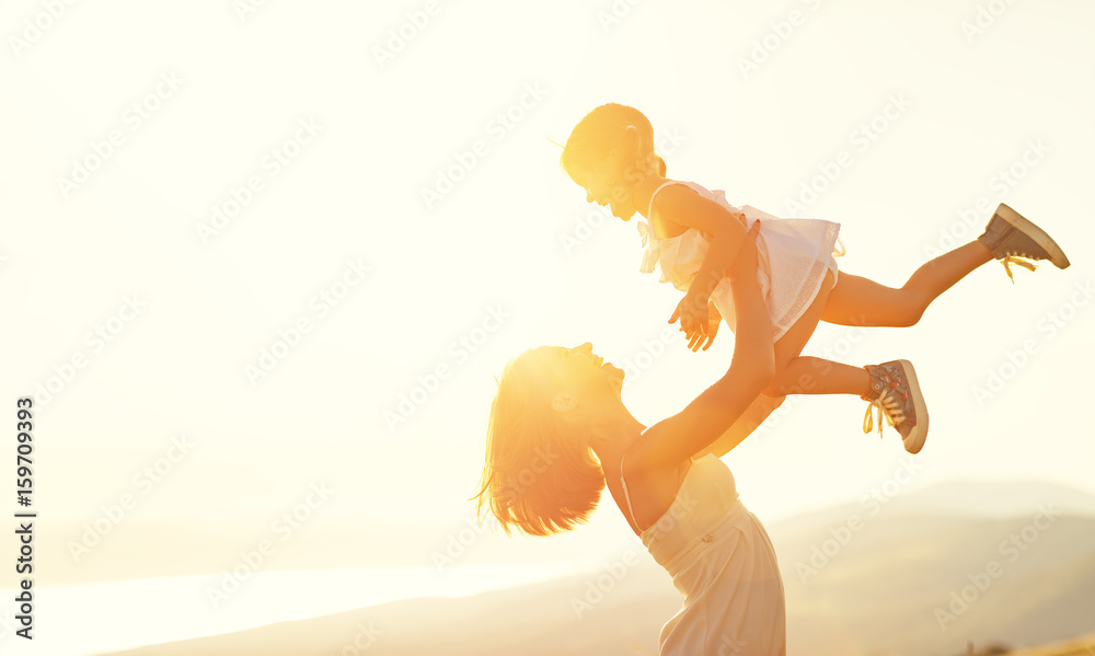 Poster Happy family in summer outdoors. The mother throws up child daughter and laughing