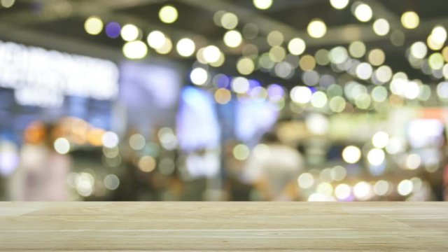 Modern smart mobile phone with on line shopping store graphic and open sign on wooden table over blur light and shadow of mall