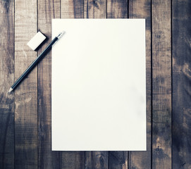 Photo of blank stationery: letterhead, pencil and eraser on vintage wooden table background. Responsive design mockup for placing your design. Top view.