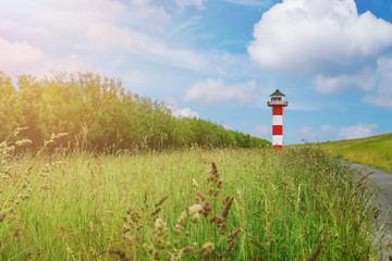 typical red and white lighthouse behind dike embankment at shore of Elbe river