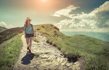 Woman hiking in mountains at sunny day time.