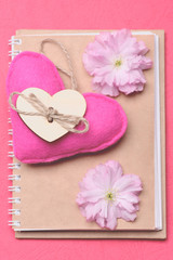 Obraz na płótnie Canvas Heart in pink colour with sakura flowers on beige diary
