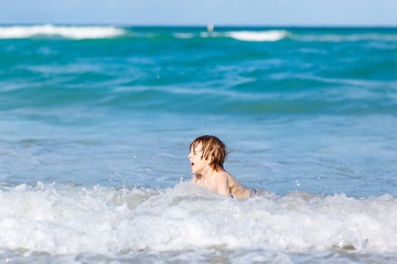 little blond kid boy having fun on ocean beach in Florida