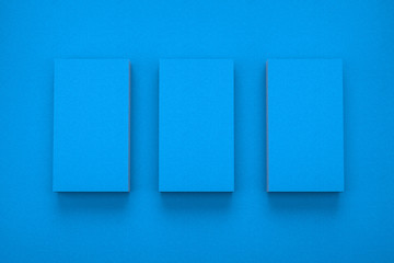 Mockup of three vertical business cards on blue textured paper studio. High resolution 3d render.