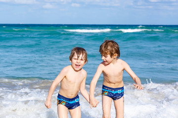 Two kid boys running on ocean beach in Florida