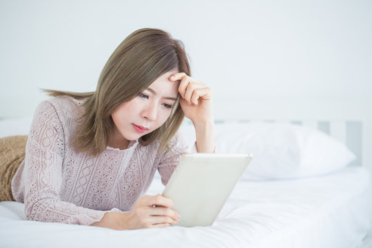 Fatigued Asian woman  with strain face, Young  stressed business woman looking computer tablet on bedroom with copy space