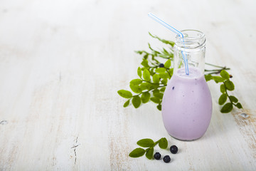 Smoothies and ripe blueberries on a wooden table.