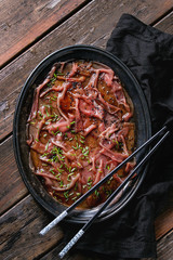 Asian style Beef carpaccio with soy sauce, chive onion, black sesame, served on vintage metal tray with textile napkin and chopsticks over old wooden plank background. Top view with space