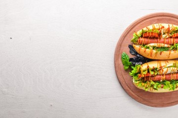 Hot dog with grilled sausage, mustard and ketchup, onions and greens on Wooden background. Top view. Free space.