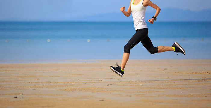 Healthy lifestyle young fitness woman running at sunny beach