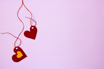 Two paper hearts tied to a string on a pink-purple background