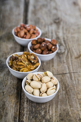 Four bowls with nuts on a  wooden table