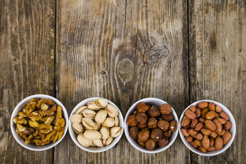 Four bowls with nuts on a  wooden table