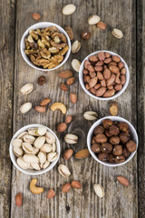 Fototapeta premium Four bowls with nuts on a wooden table