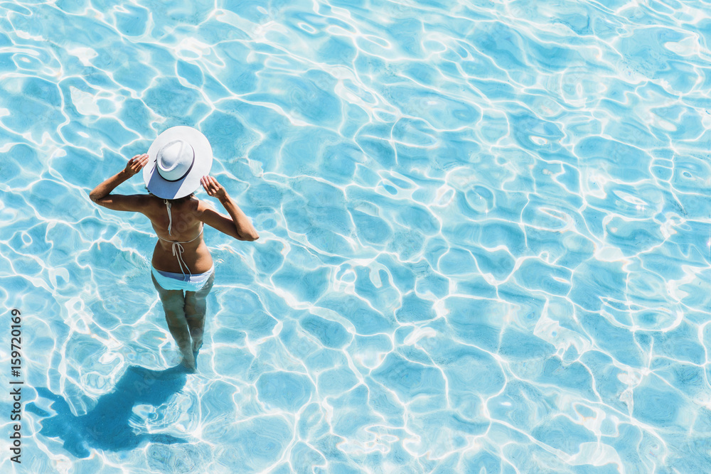 Wall mural young beautiful woman standing in the sea and enjoying summer. summer vacation concept.