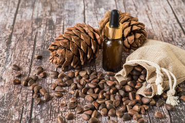  Cedar cones, nuts and oil. Cedar cones, a small sack with nuts and a bottle of oil on an old wooden background.