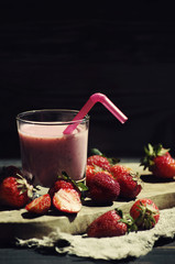 Milkshake with strawberry berries. Strawberry smuz in a glass with a tubule on a wooden board
