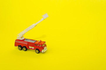 miniature red color fire truck on yellow background, toy car, selective focus, copy space