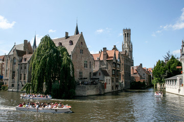 Cityscape of Bruges, Flanders, Belgium. Water canal at Rozenhoedkaai with old brick buildings and Belfry Tower on background.