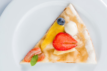 Piece of sweet pizza with strawberries on a plate