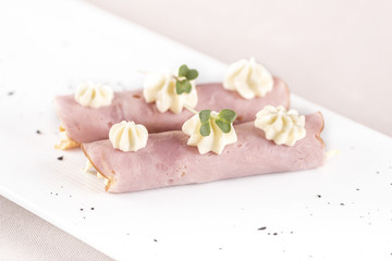 Obraz na płótnie Canvas Fresh appetizer with ham and Coleslaw salad, decorated with mayonnaise and green leaf, placed on white plate, light background, isolated
