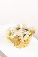 Appetizer with Caeser Salad and chicken fillet, served in a parmesan basket, white plate, light background