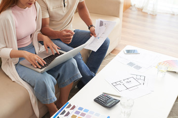 High angle shot of young couple discussing housing plans and using laptop