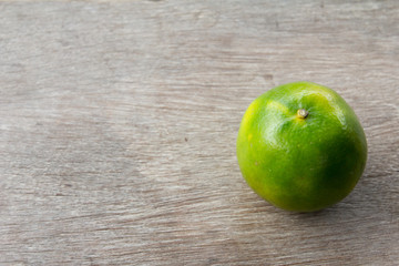 One green color lime on wooden table background