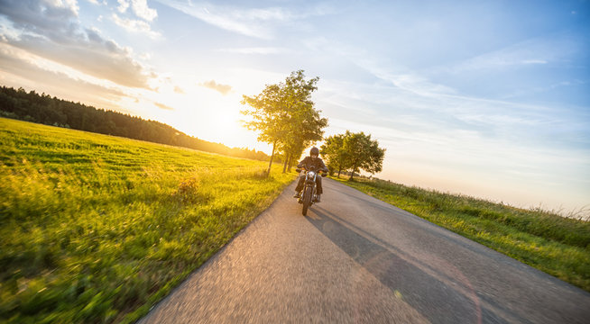 Dark motorbiker riding high power motorbike in sunset