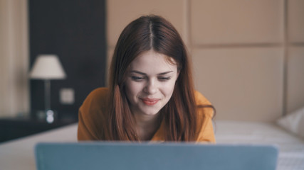 Woman looks at laptop, woman lies in bed