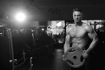 Fototapeta na wymiar Caucasian fitness model lifting weight in gym