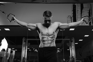 Fototapeta na wymiar Male fitness model with naked torso posing in gym